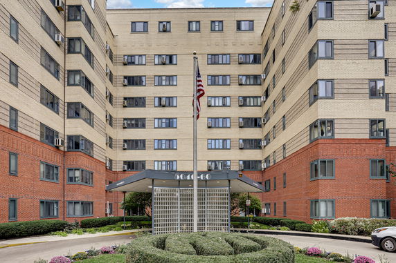 Front view of a multi-story residential building with brick and light-colored facade.