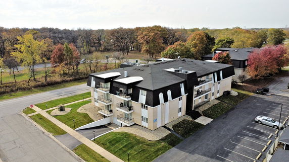 Aerial view of a multi-story residential building with multiple balconies and a dark roof.