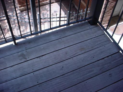 Rooftop with wooden deck flooring and a metal railing.