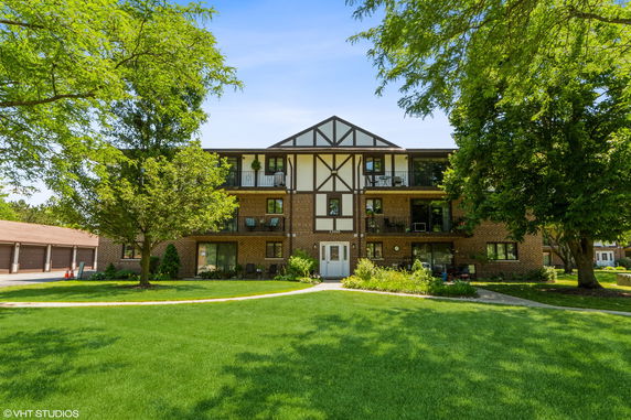Front view of a three-story building with a brick facade and balconies.