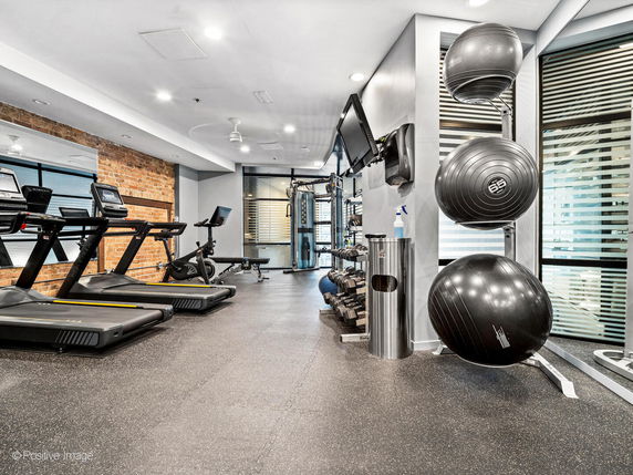 Indoor gym area with treadmills, exercise bikes, dumbbells, and stability balls.