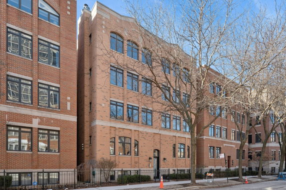 Front view of a multi-story brick building with numerous windows and a central entrance.