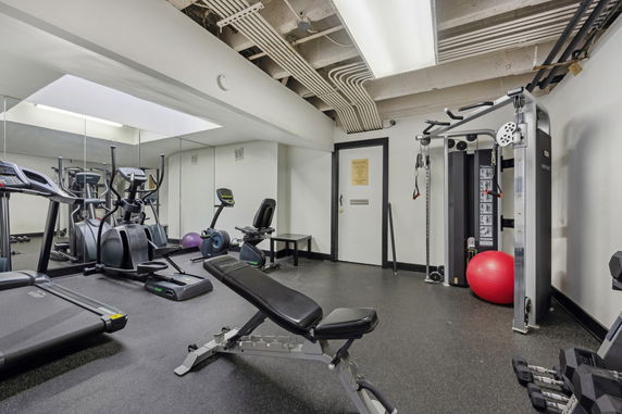 Indoor gym area with exercise equipment and weights.