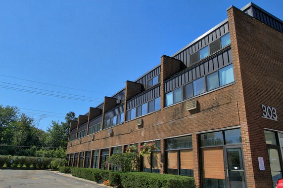 Front view of a multi-story brick building with large windows and air conditioning units.