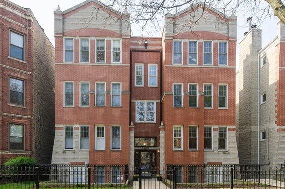 Front view of a multi-story brick apartment building with multiple windows.