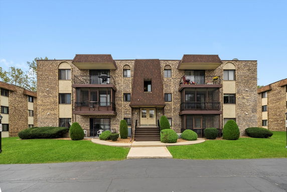 Front view of a multi-story building with balconies and brick facade.
