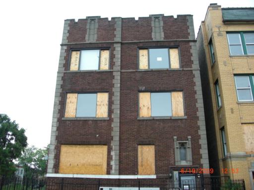 Front view of a three-story brick building with boarded-up windows.