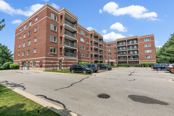 Front view of a multi-story brick apartment building with balconies.