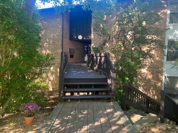 Elevated front entrance of a brick building with a pathway and stairs.