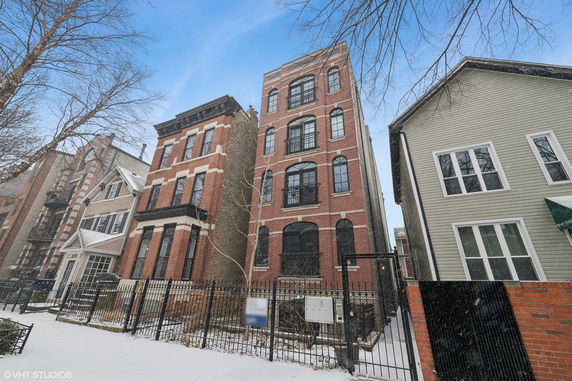 Front view of a multi-story brick apartment building with large windows.