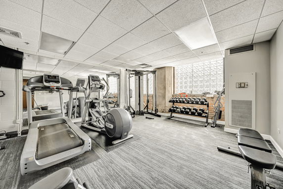 Indoor gym area with fitness equipment, including treadmills and a set of weights.