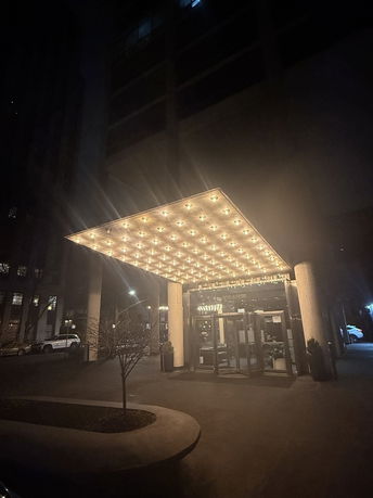 Front view of a building with an illuminated canopy entrance at night.