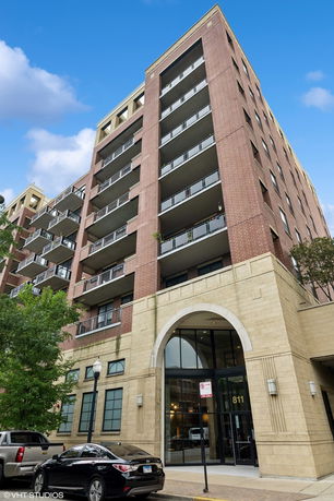 Front view of a multi-story brick apartment building with balconies.