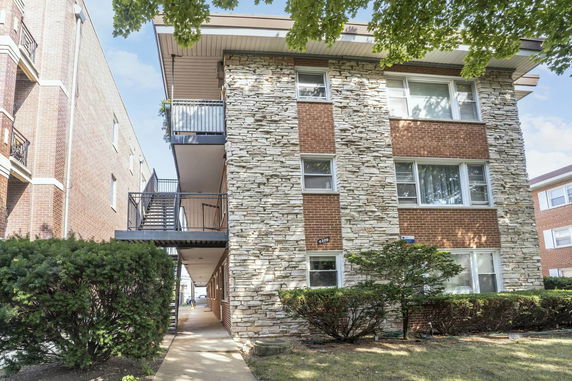 Front view of a multi-story apartment building with brick and stone facade.