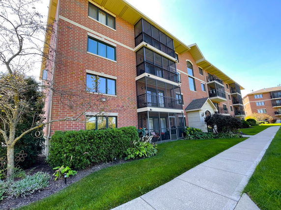 Front view of a multi-story brick apartment building with balconies.