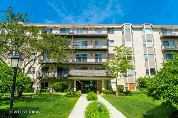 Front view of a multi-story apartment building with balconies and a prominent entrance.