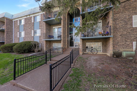 Front view of a multi-story brick apartment building with balconies.