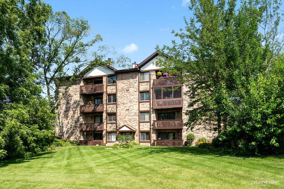 Front view of a multi-story apartment building with balconies and brick facade.