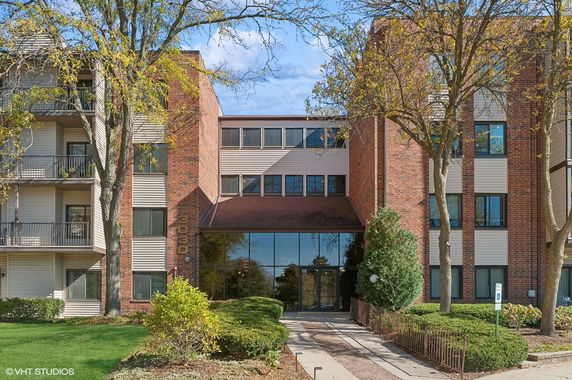 Front view of a multi-story residential building with brick facade and large windows.