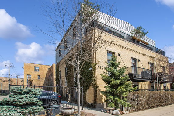 Front view of a multi-story house with a glass balcony and brick facade.