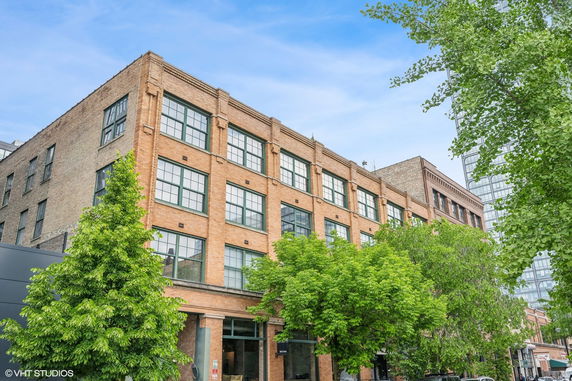 Front view of a multi-story brick building with large windows.
