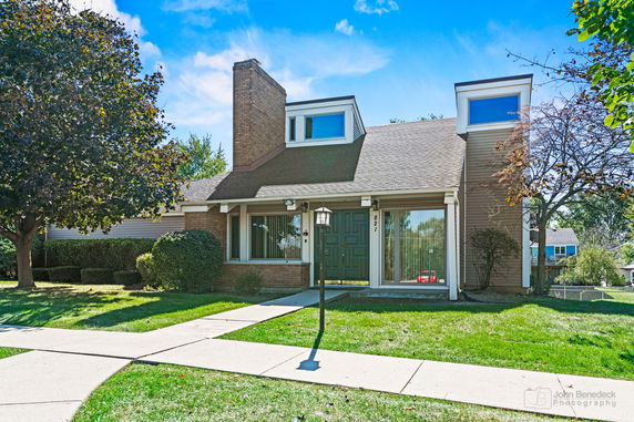 Front view of a house with a sloped roof and large windows.