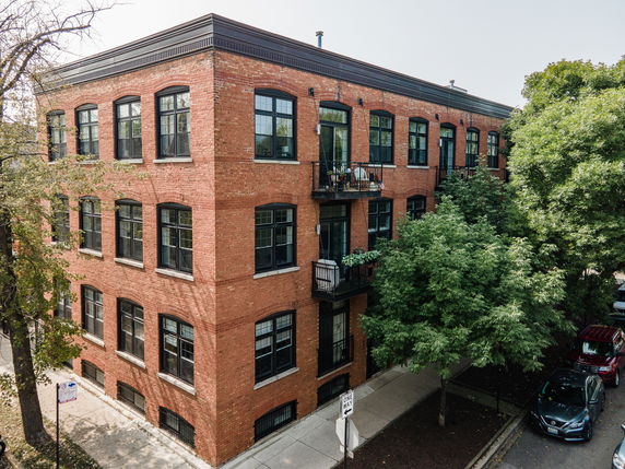 Front view of a three-story brick apartment building with multiple windows and balconies.