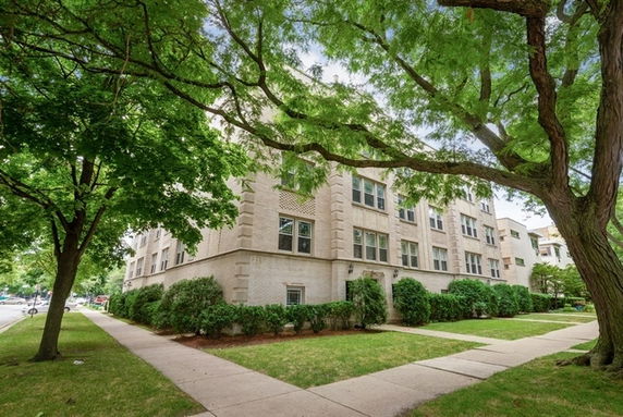 Front view of a multi-story apartment building with a brick facade and multiple windows.