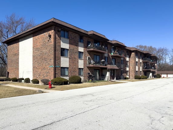 Front view of a three-story brick apartment building with balconies.