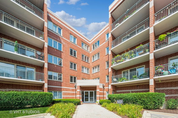 Front view of a multi-story brick apartment building with balconies.