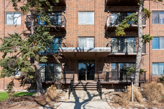 Front view of a multi-story brick apartment building with balconies.
