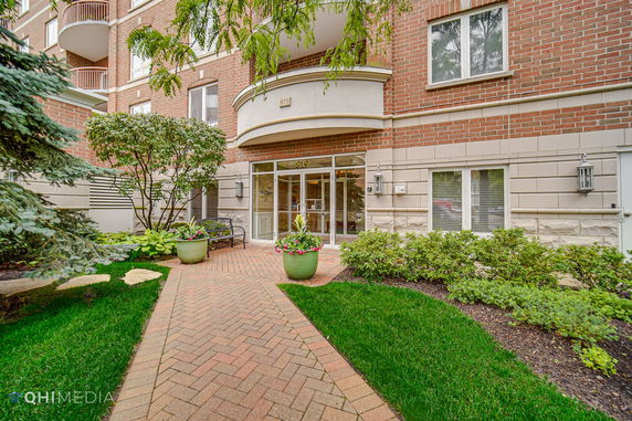 Front view of a multi-story building entrance with brick facade and large glass doors.