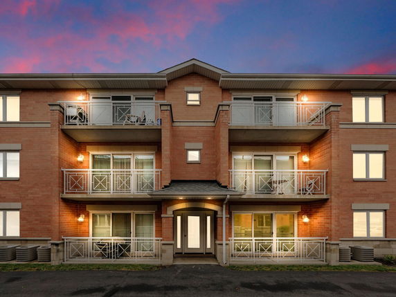 Front view of a three-story brick apartment building with balconies.