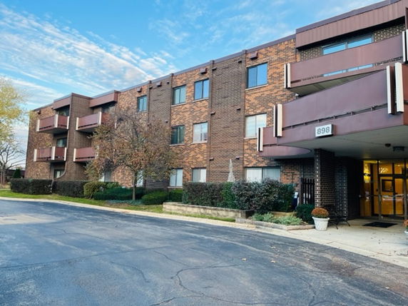Front view of a three-story brick apartment building with balconies.