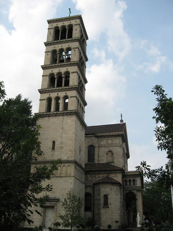 Front view of a multi-story stone building with a tower and arches.