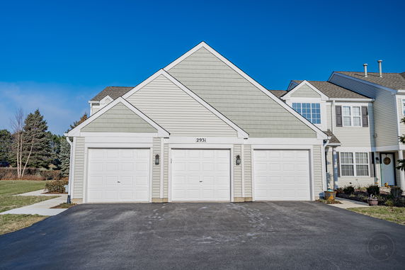 Front view of a house with three garage doors and peaked roofs.
