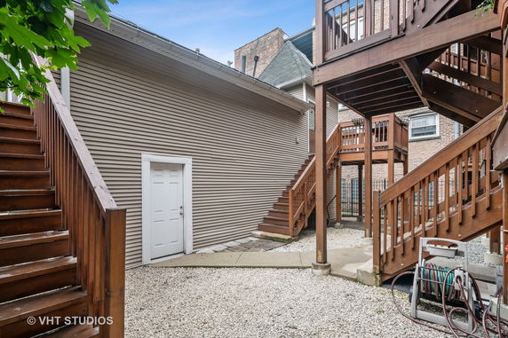 Back exterior view of a house with wooden stairs and a door.