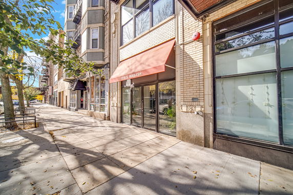 Front view of a multi-story building with a red awning.