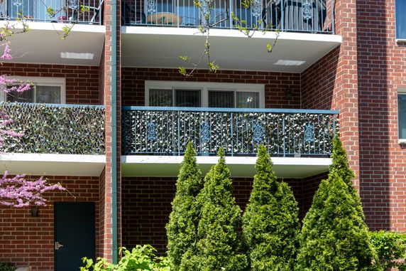 Front view of a multi-story building with brick exterior and balconies.