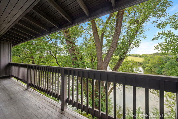 View from a covered balcony overlooking a river and trees.