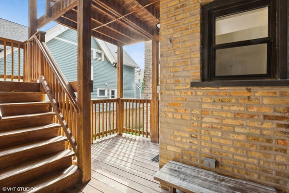 View of a wooden staircase and railing with a brick wall.