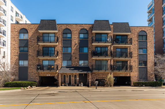 Front view of a multi-story brick apartment building with balconies.
