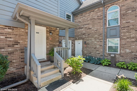 Front view of a residential building entrance with brick and siding exterior.