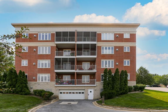 Front view of a multi-story brick apartment building with balconies.