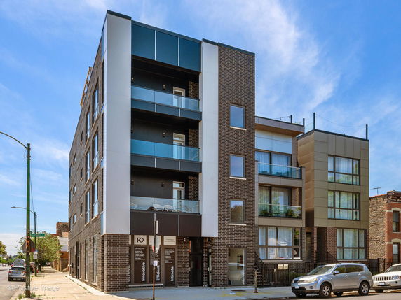 Front view of a modern multi-story building with brick exterior and balconies.
