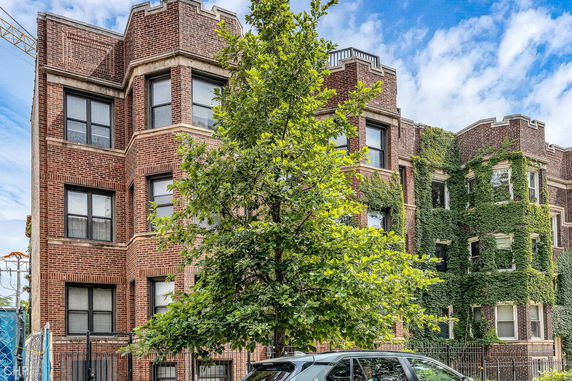 Front view of a multi-story brick building with large windows and climbing ivy.