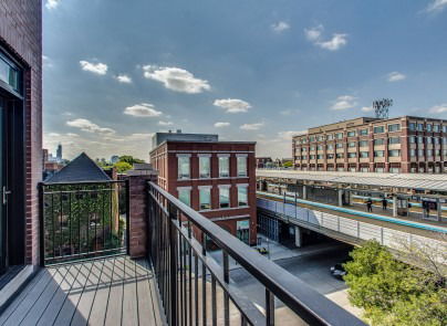 Panoramic view from a balcony overlooking urban buildings and a railway station.