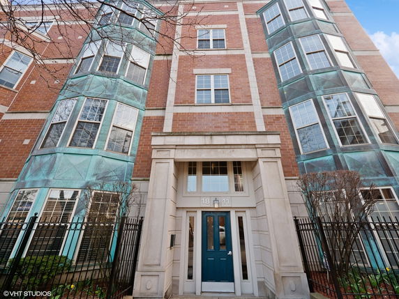 Front view of a multi-story brick building with distinctive teal bay windows.