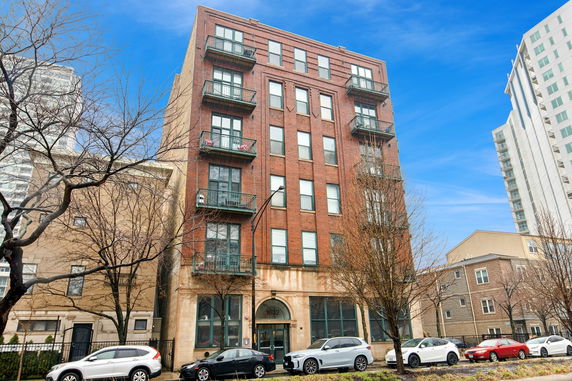 Front view of a multi-story brick apartment building with multiple balconies.