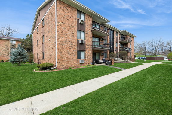 Front view of a multi-story brick apartment building with balconies.